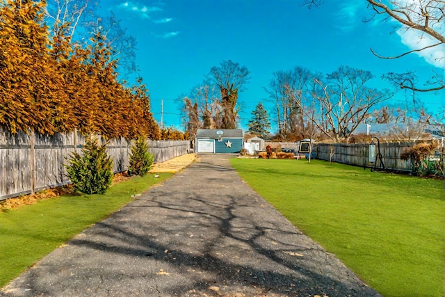 view of yard with a detached garage, fence, and an outdoor structure