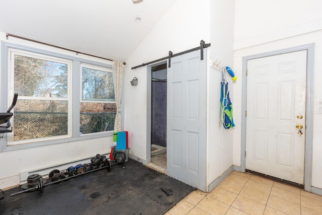 interior space featuring lofted ceiling, a barn door, and light tile patterned flooring