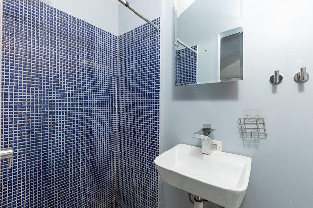 full bath featuring a tile shower and a sink