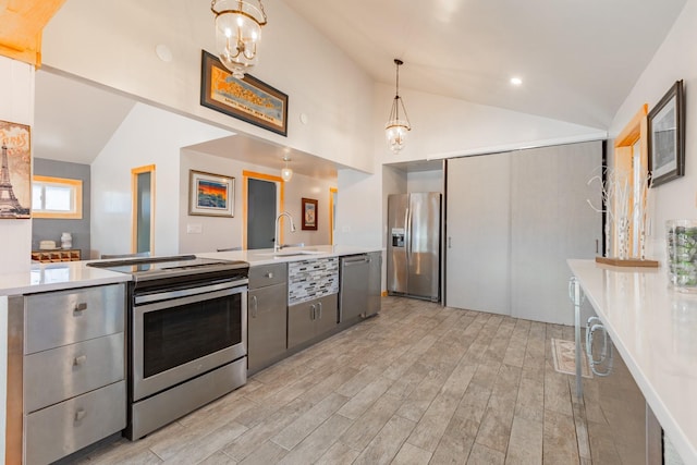 kitchen featuring vaulted ceiling, light countertops, appliances with stainless steel finishes, and gray cabinets