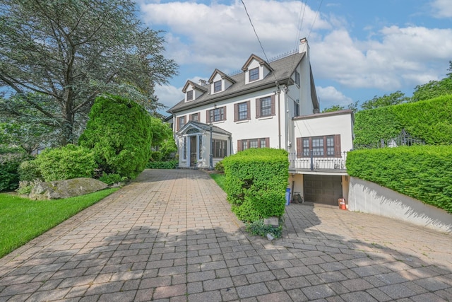 view of front of home featuring an attached garage, a chimney, decorative driveway, and stucco siding