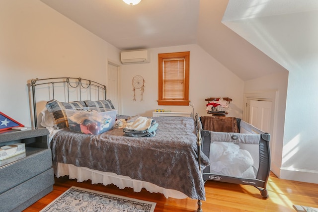 bedroom with wood finished floors, vaulted ceiling, and a wall mounted AC