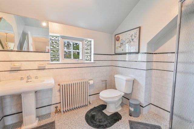 bathroom featuring toilet, lofted ceiling, radiator heating unit, speckled floor, and tile walls