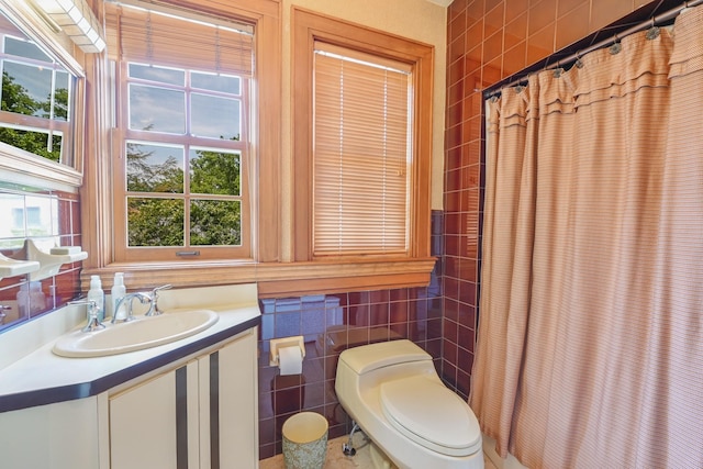 bathroom with a shower with shower curtain, vanity, toilet, and tile walls