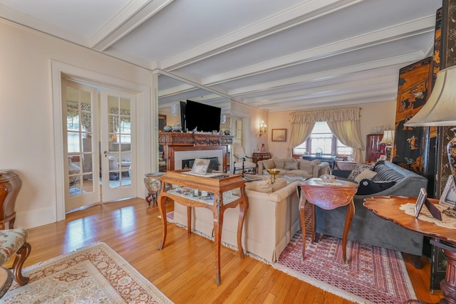 living area featuring beam ceiling, french doors, a fireplace, light wood-style flooring, and baseboards