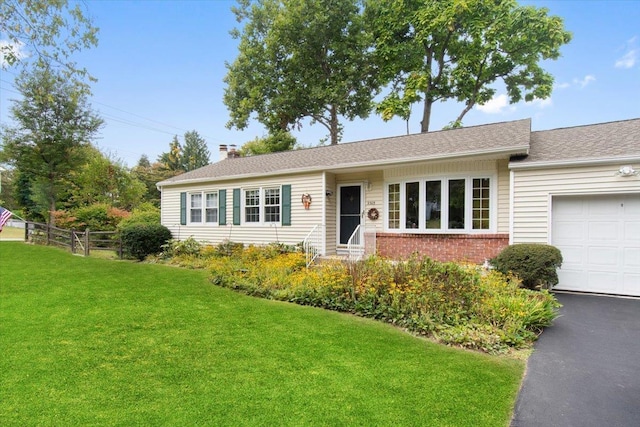 single story home featuring aphalt driveway, an attached garage, brick siding, fence, and a front yard