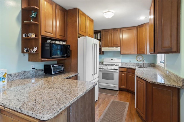 kitchen with a toaster, open shelves, a peninsula, white appliances, and under cabinet range hood