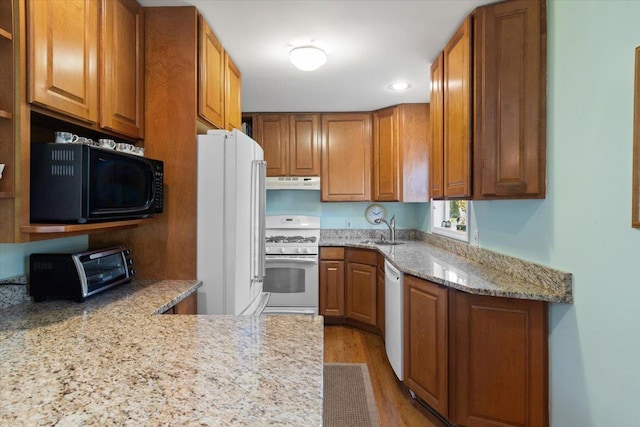 kitchen with brown cabinets, white appliances, a sink, and under cabinet range hood