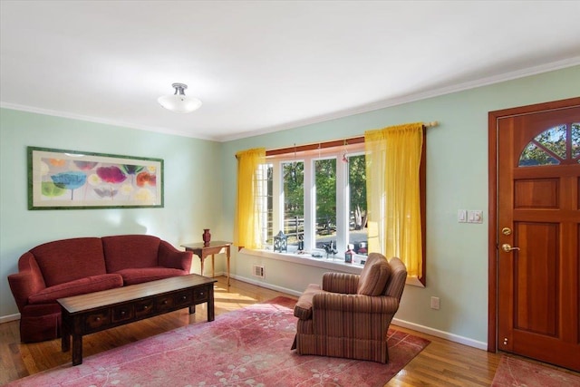 living area featuring crown molding, baseboards, and wood finished floors