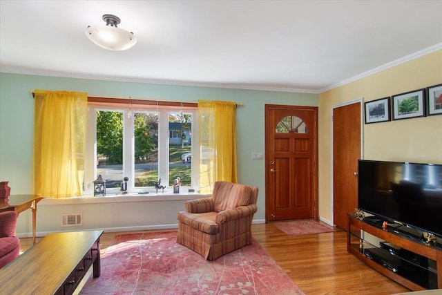 living room with baseboards, visible vents, wood finished floors, and ornamental molding