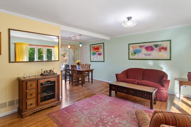 living room with ornamental molding, visible vents, baseboards, and wood finished floors