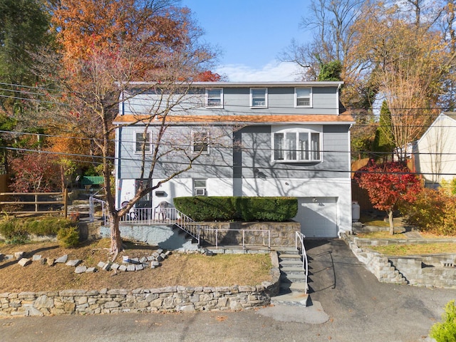 view of front of home featuring a garage, fence, and aphalt driveway