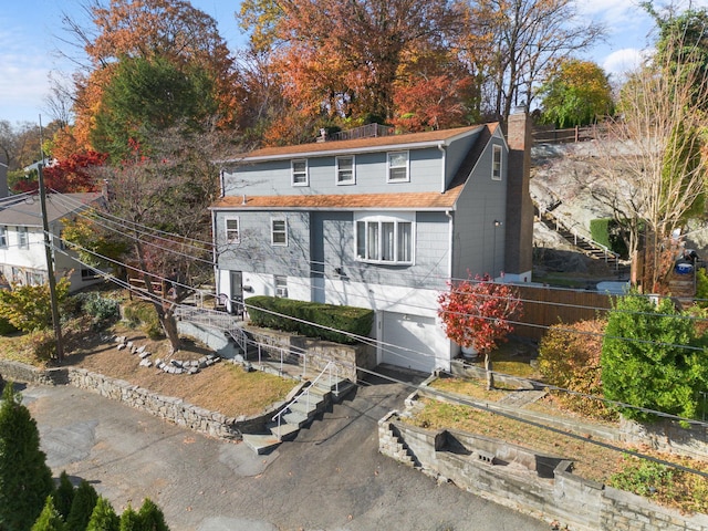 view of front of house with a garage, a chimney, and aphalt driveway