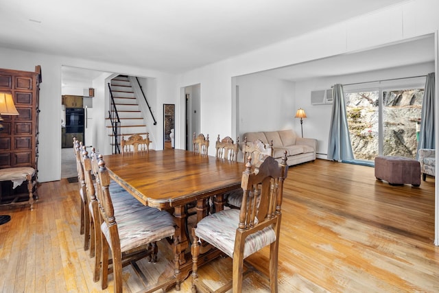 dining room with stairs, a baseboard radiator, and light wood-style floors