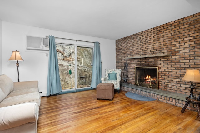 living room with an AC wall unit, a fireplace, baseboard heating, and wood finished floors