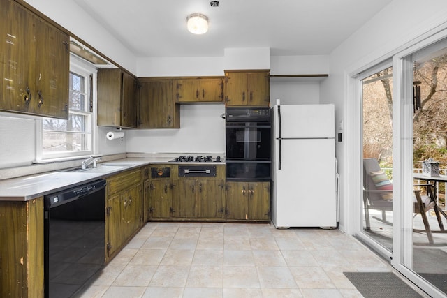 kitchen featuring a warming drawer, light tile patterned floors, light countertops, a sink, and black appliances