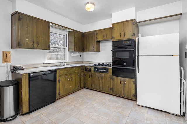 kitchen featuring a sink, black appliances, light countertops, and a warming drawer