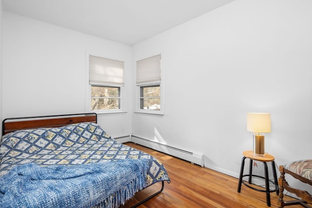 bedroom with baseboard heating, wood finished floors, and baseboards