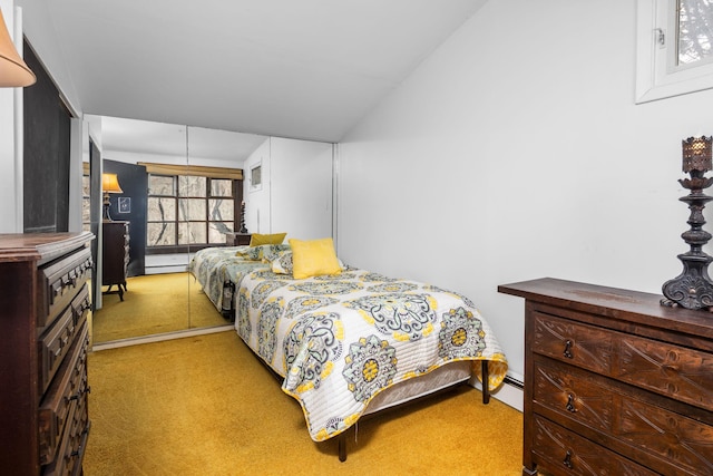 carpeted bedroom with baseboard heating and vaulted ceiling