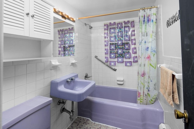 bathroom featuring shower / bathtub combination with curtain, a sink, and tile walls