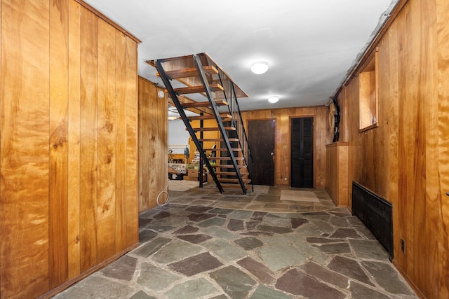 hallway with stairway, stone floors, and wooden walls