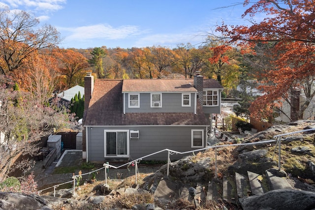 rear view of house featuring roof with shingles, fence, a chimney, and a wall unit AC