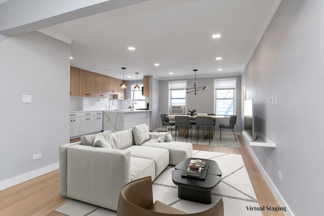 living room featuring light wood-type flooring, crown molding, baseboards, and recessed lighting