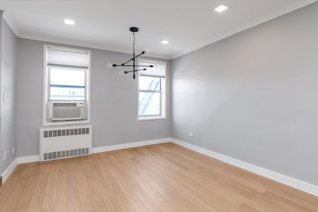 unfurnished dining area featuring baseboards, light wood-type flooring, cooling unit, and radiator