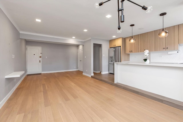 kitchen with light wood-type flooring, light countertops, stainless steel fridge, and baseboards