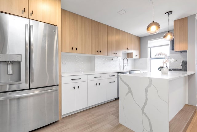 kitchen featuring stainless steel appliances, tasteful backsplash, a peninsula, and a sink