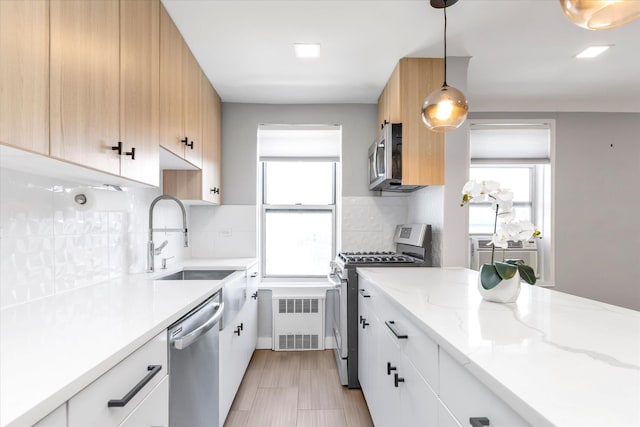 kitchen with stainless steel appliances, a wealth of natural light, a sink, and tasteful backsplash