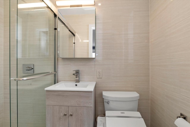 full bath featuring tile walls, a shower stall, vanity, and toilet