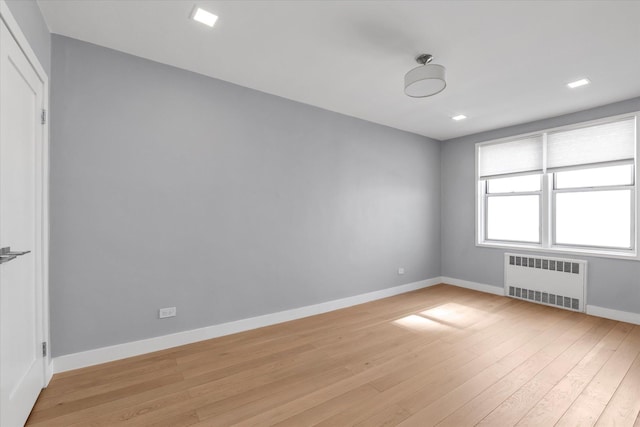 unfurnished room with light wood-style floors, radiator heating unit, and baseboards