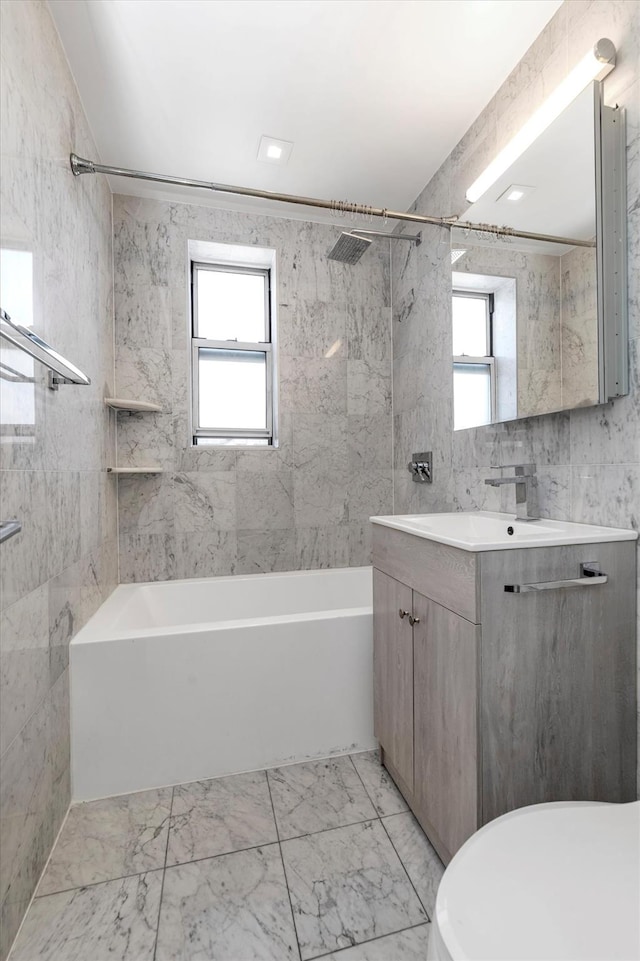 full bathroom with marble finish floor, bathtub / shower combination, tile walls, and vanity