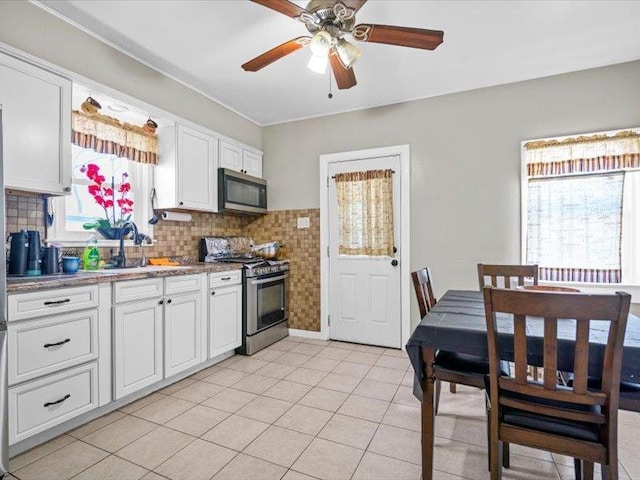 kitchen featuring light tile patterned floors, a sink, white cabinetry, appliances with stainless steel finishes, and decorative backsplash