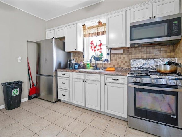 kitchen with light tile patterned floors, a sink, white cabinetry, appliances with stainless steel finishes, and backsplash