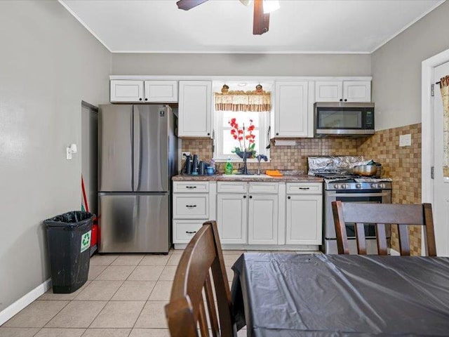 kitchen featuring light tile patterned floors, a sink, white cabinetry, appliances with stainless steel finishes, and tasteful backsplash