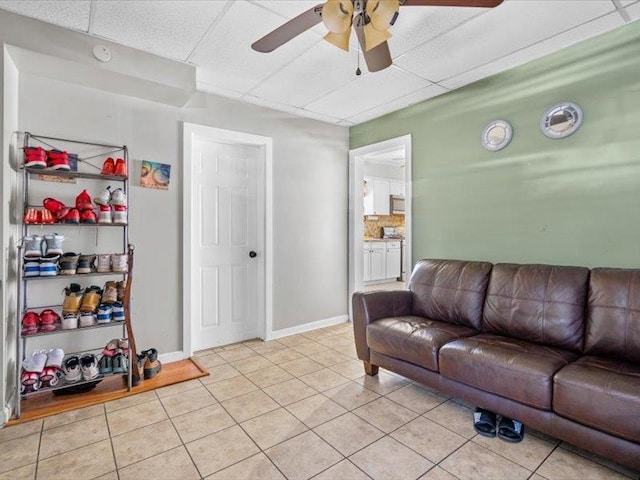 living area featuring ceiling fan, baseboards, and light tile patterned flooring