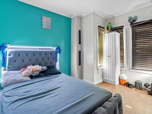 bedroom featuring baseboards, wood finished floors, and crown molding