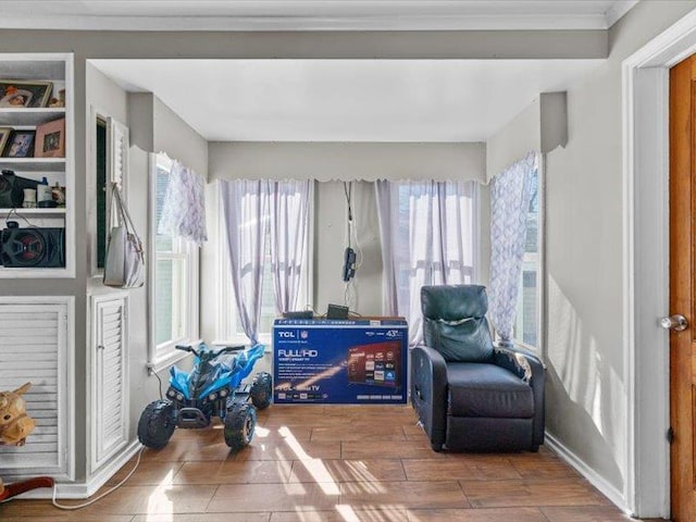 living area with wood finish floors, crown molding, and baseboards