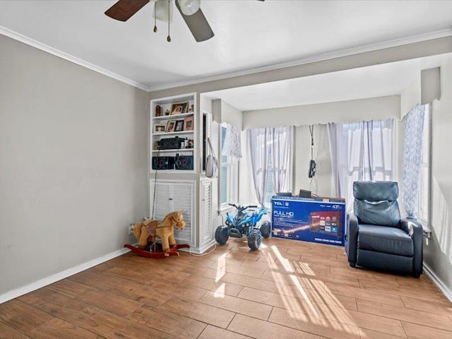 living area with ornamental molding, wood finished floors, built in shelves, and baseboards