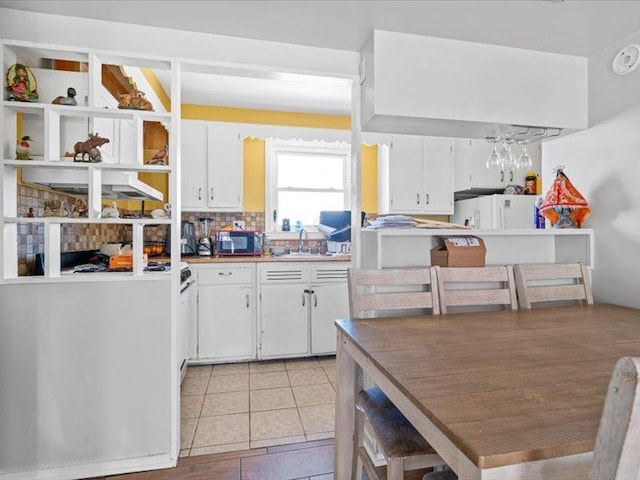 kitchen featuring white cabinets, a sink, white fridge, and light tile patterned flooring