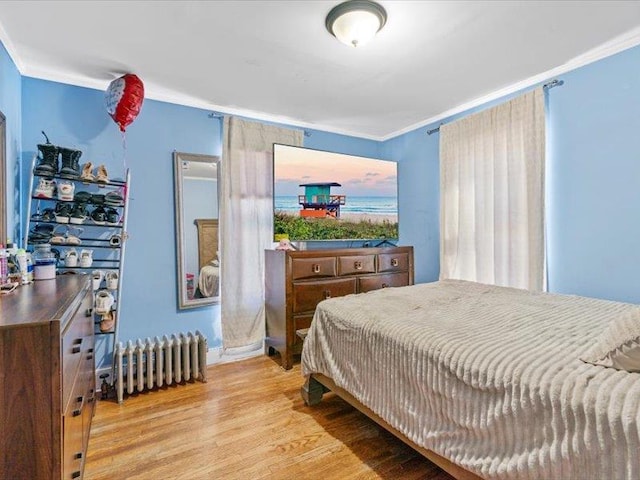 bedroom with crown molding, wood finished floors, and radiator