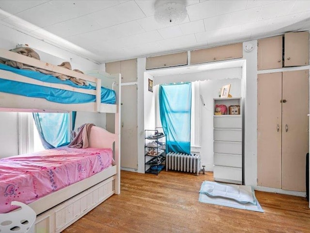 bedroom with radiator heating unit and wood finished floors