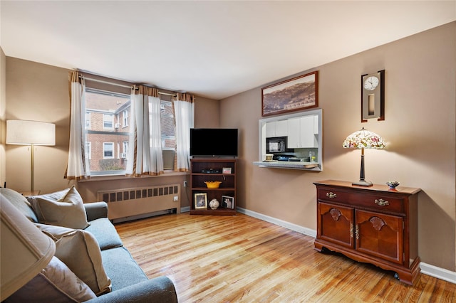 living area with light wood finished floors, radiator heating unit, and baseboards