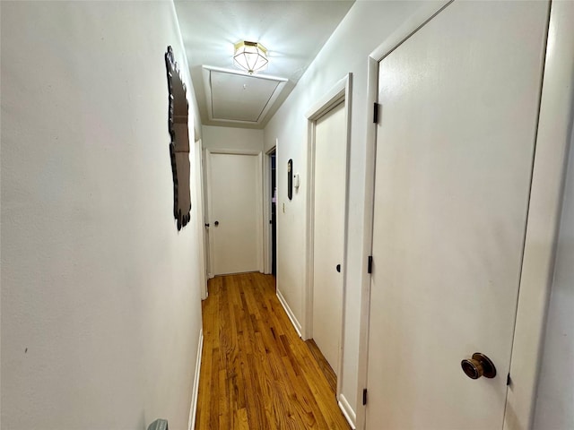 hall featuring attic access and light wood finished floors