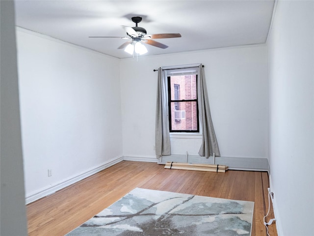 empty room with ceiling fan, wood finished floors, and baseboards