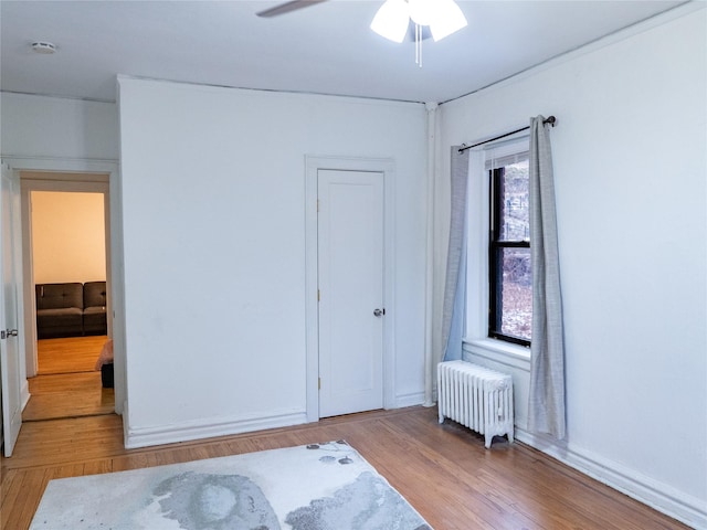 bedroom featuring radiator, light wood-style floors, and a ceiling fan