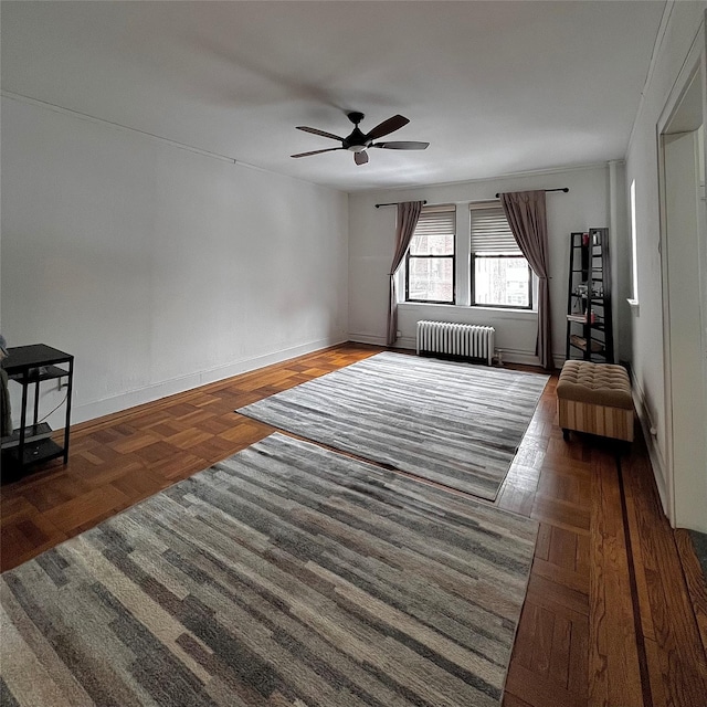 interior space with baseboards, a ceiling fan, and radiator