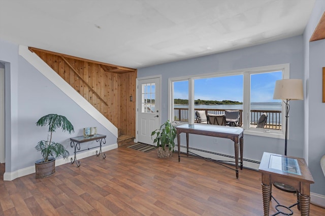 living area featuring stairs, baseboard heating, wood finished floors, and baseboards